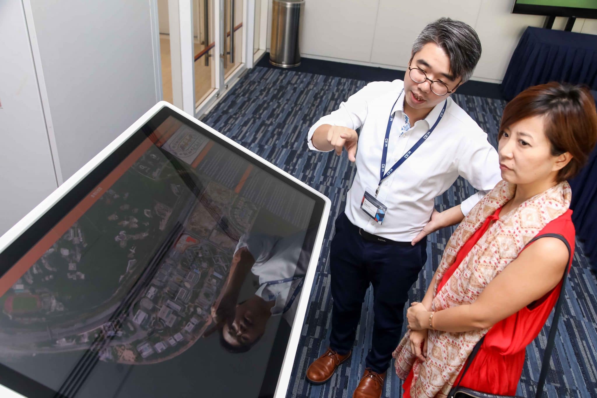 Dr. Maggie Mai from Hong Kong Science and Technology Park listened to the introduction of touch table by Wisdom Chan, Chain Technology Officer from Chain Technology Development.